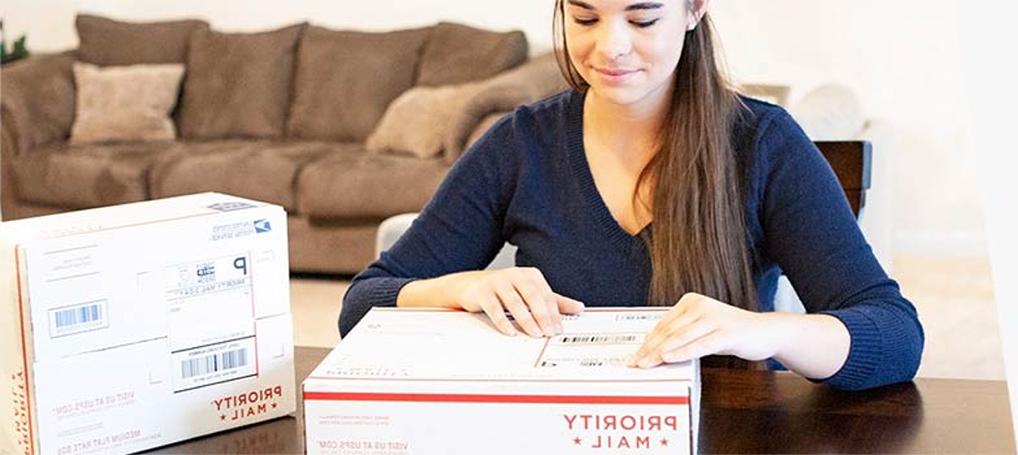 Woman attaching a shipping label to a 优先邮件 box.